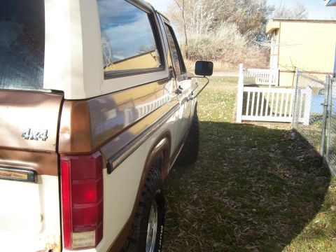 1985 Ford Bronco - This Ford Bronco features a two-tone paint scheme and 4x4 badging, seen parked outdoors.