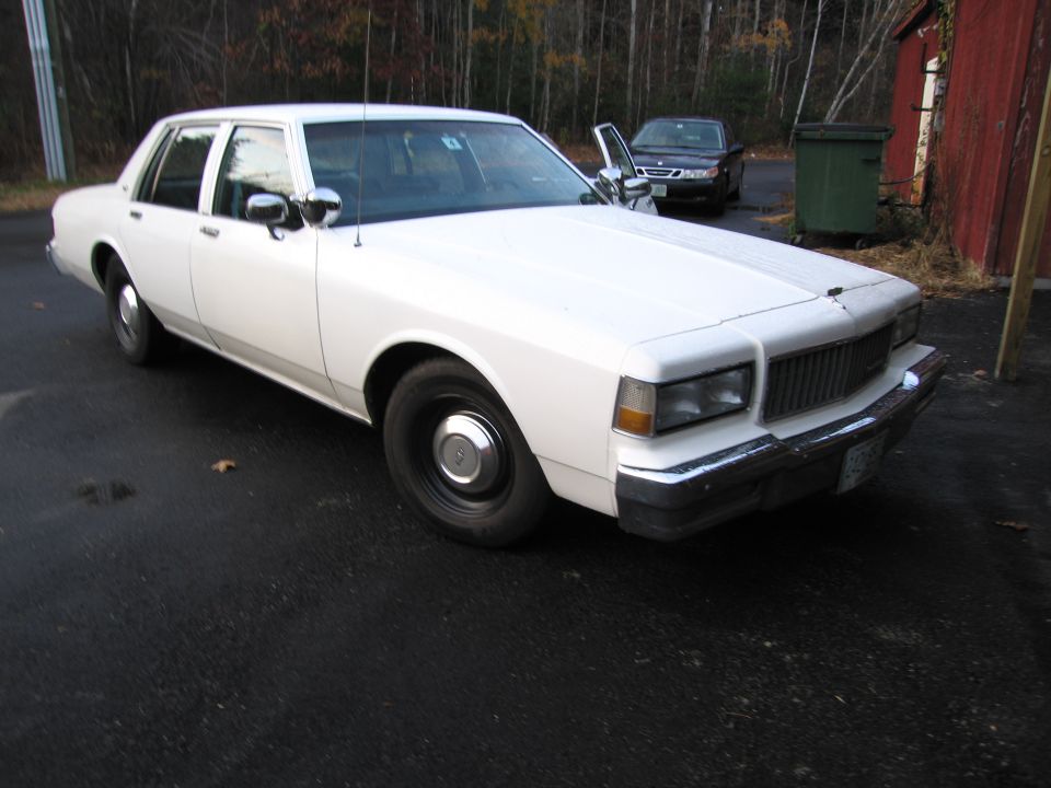 White sedan with chrome trim and steel wheels parked on asphalt