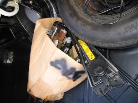 1991 Ford LTD Crown Victoria - The trunk of a car contains a spare tire, jack, and a box filled with various car parts.