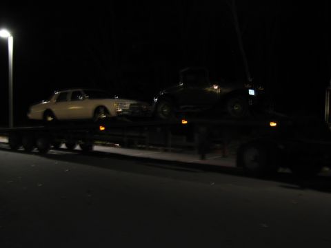 1991 Ford LTD Crown Victoria - A white 1991 Ford Crown Victoria LTD and an older dark car are transported on a flatbed trailer at night.