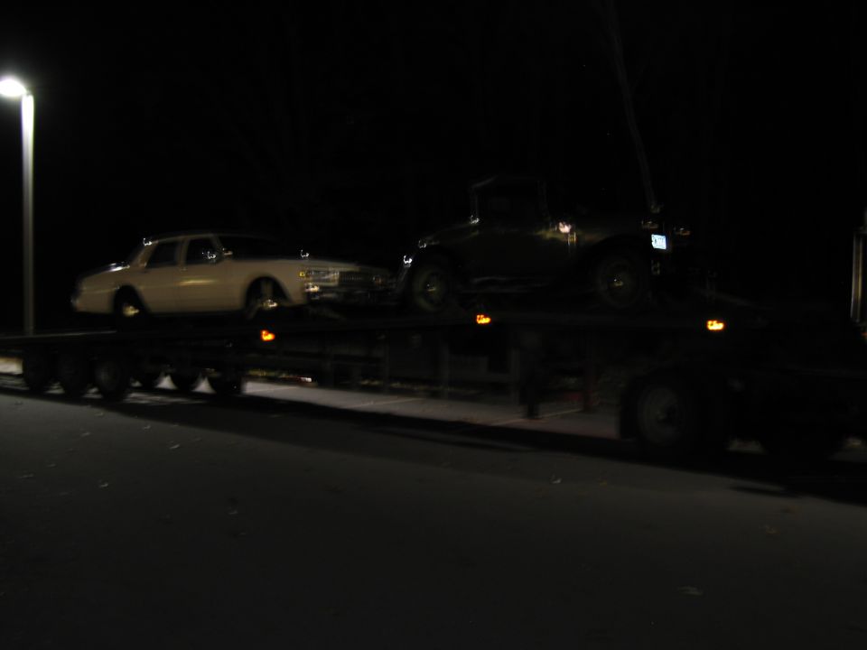 White 1991 Ford Crown Victoria LTD on a flatbed trailer at night, viewed from the side