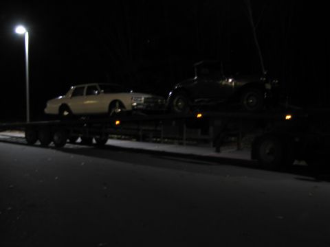 1991 Ford LTD Crown Victoria - Two vehicles are transported on a flatbed trailer under a streetlamp at night.