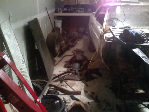 1969 Ford Mustang - A car is in a garage, surrounded by various parts and equipment, suggesting ongoing maintenance or restoration.