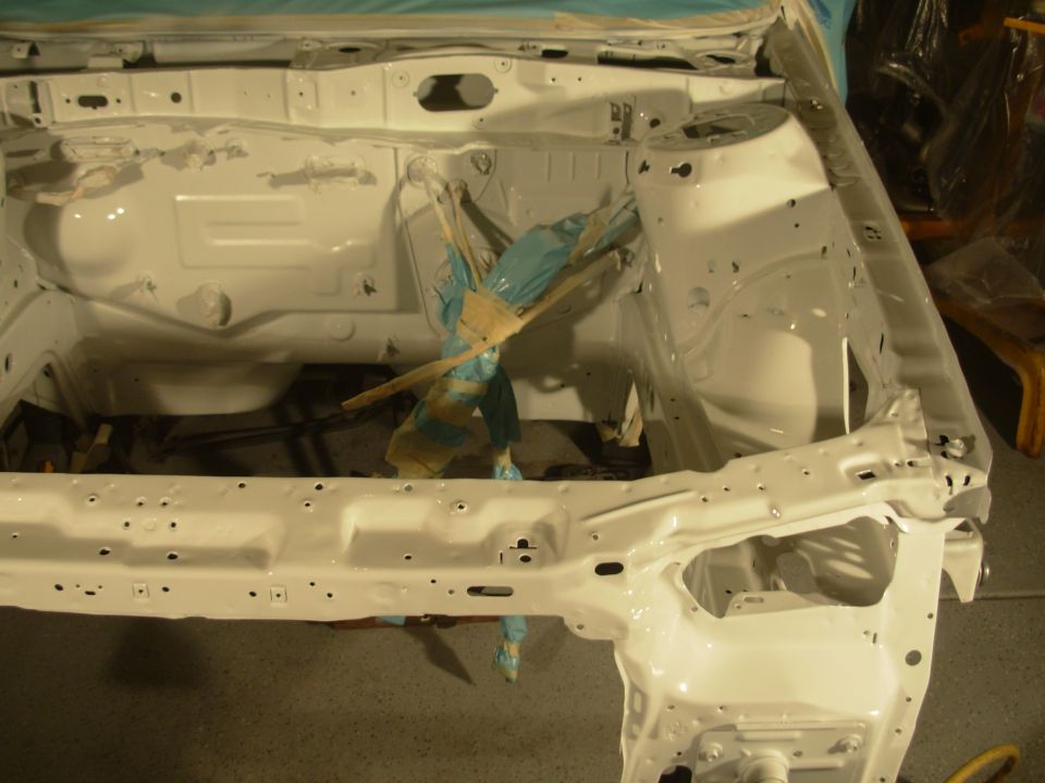 White painted car engine bay frame with some blue plastic covering