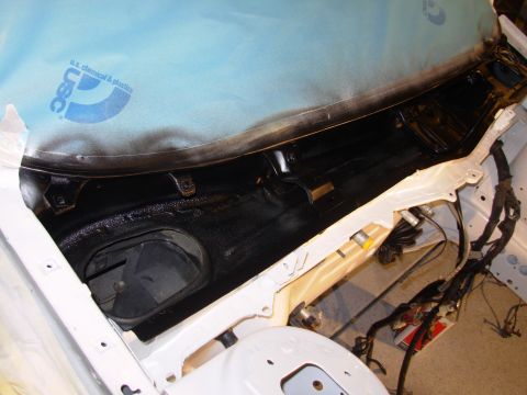 1991 Ford Taurus - The cowl area of a car is being worked on, with black sealant applied and protective sheeting in place.