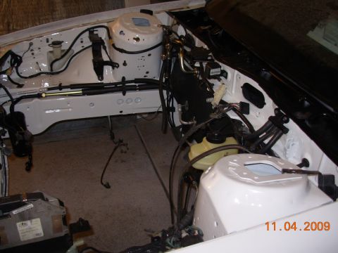 1991 Ford Taurus - The engine bay of a white vehicle is shown with various hoses and wiring disconnected.