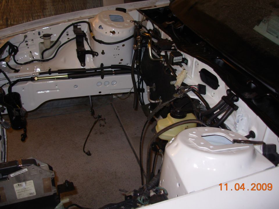 White engine bay with exposed wiring and components, viewed from above