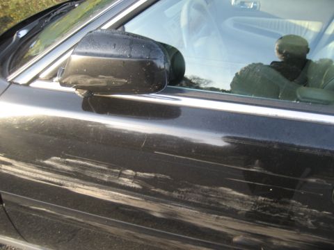 1997 Acura TL - Close-up of a car's side door and side mirror, showing damage and a reflection.