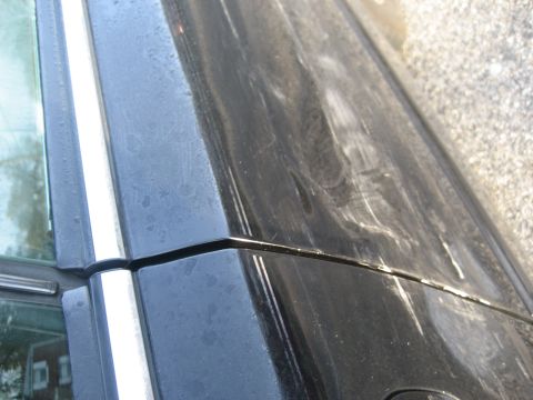 1997 Acura TL - Close-up of a black car's side door and window trim, showing water spots and scuffs.