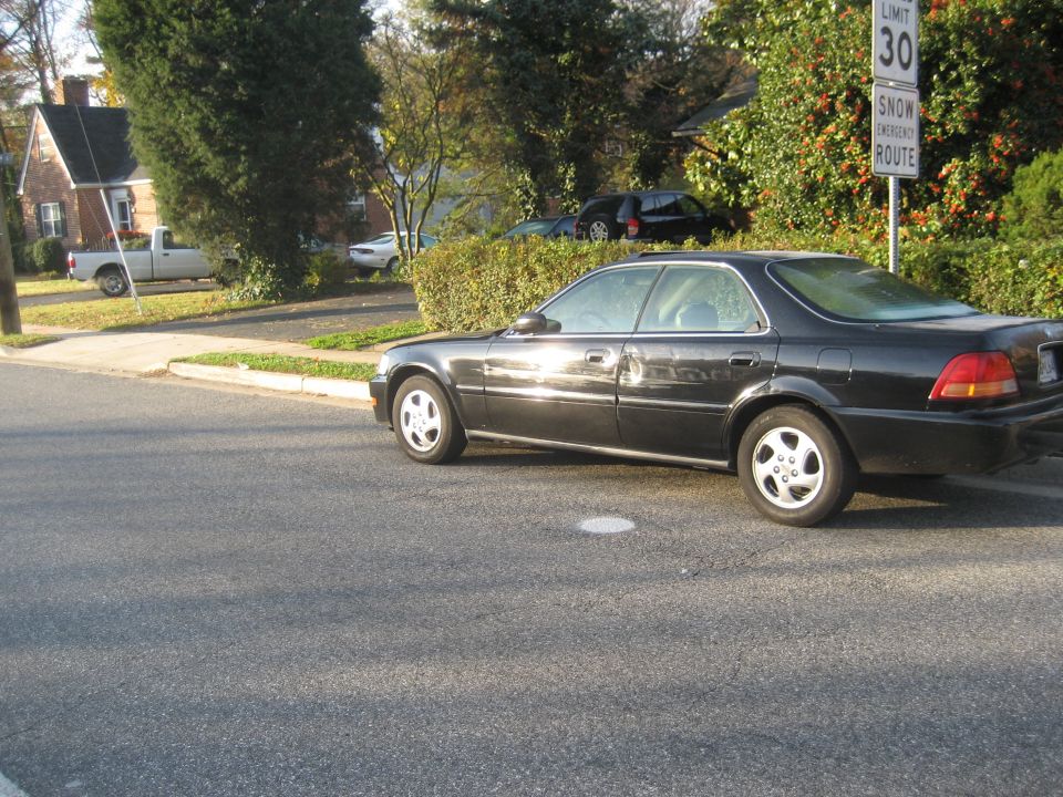 1997 Acura TL sedan parked curbside, side view. Another car and a pickup truck are visible in the background