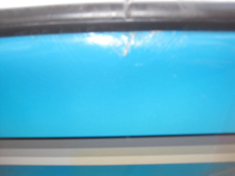 Close-up of a blue boat hull with a black trim piece above it. Supermotors.net logo visible