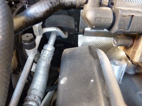 2003 Volkswagen Beetle - Detail shot of various hoses and a black electrical component within a vehicle's engine compartment.