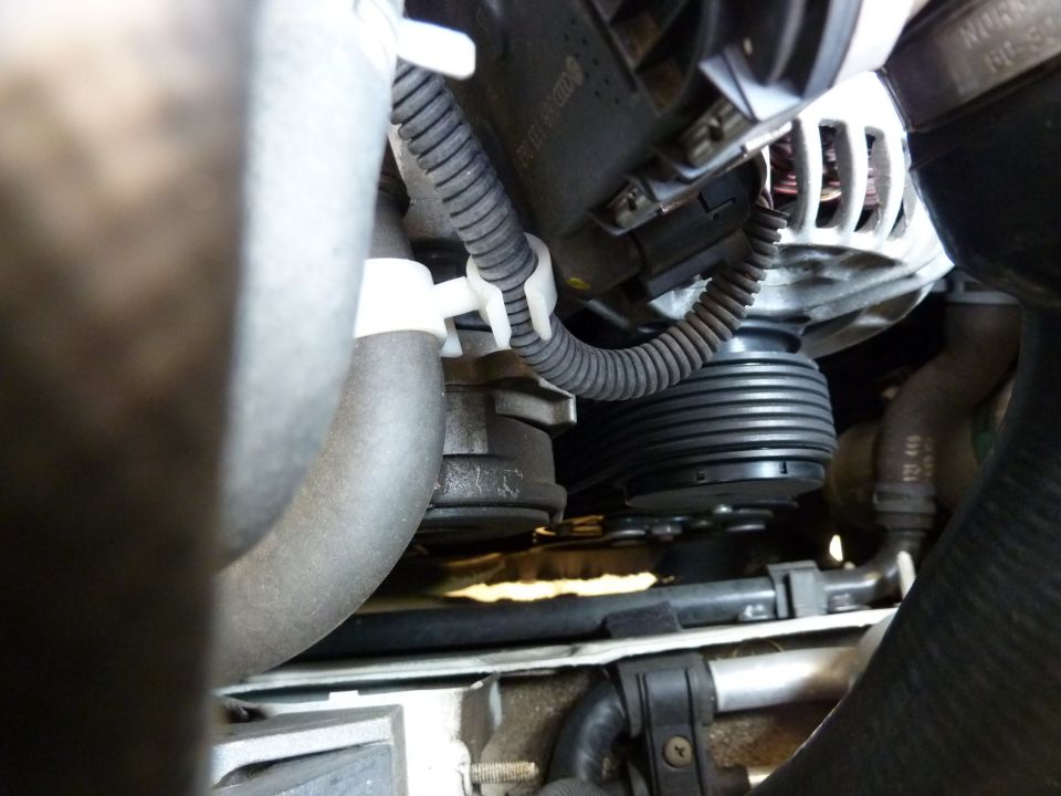 Close-up of engine belt and alternator with hoses and wiring