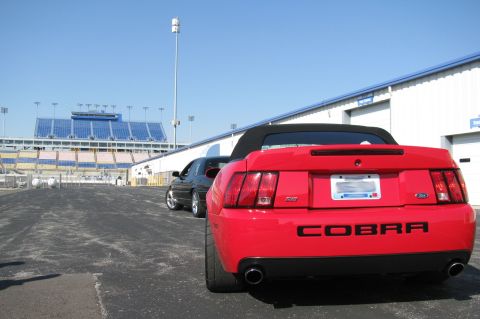 2003 Mercury Marauder - Rear view of a red convertible with a COBRA emblem, parked near a stadium.