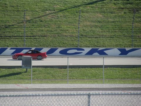 2003 Mercury Marauder - A red coupe with a black top drives on a racetrack, with 'Kentucky' visible on the wall behind it.
