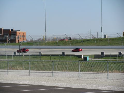 2003 Mercury Marauder - Two red cars are visible on a race track with a building and fence line.