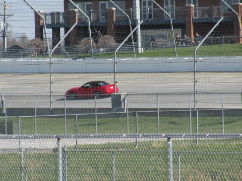 2003 Mercury Marauder - A red coupe with a black roof is seen on a racetrack, behind a fence.