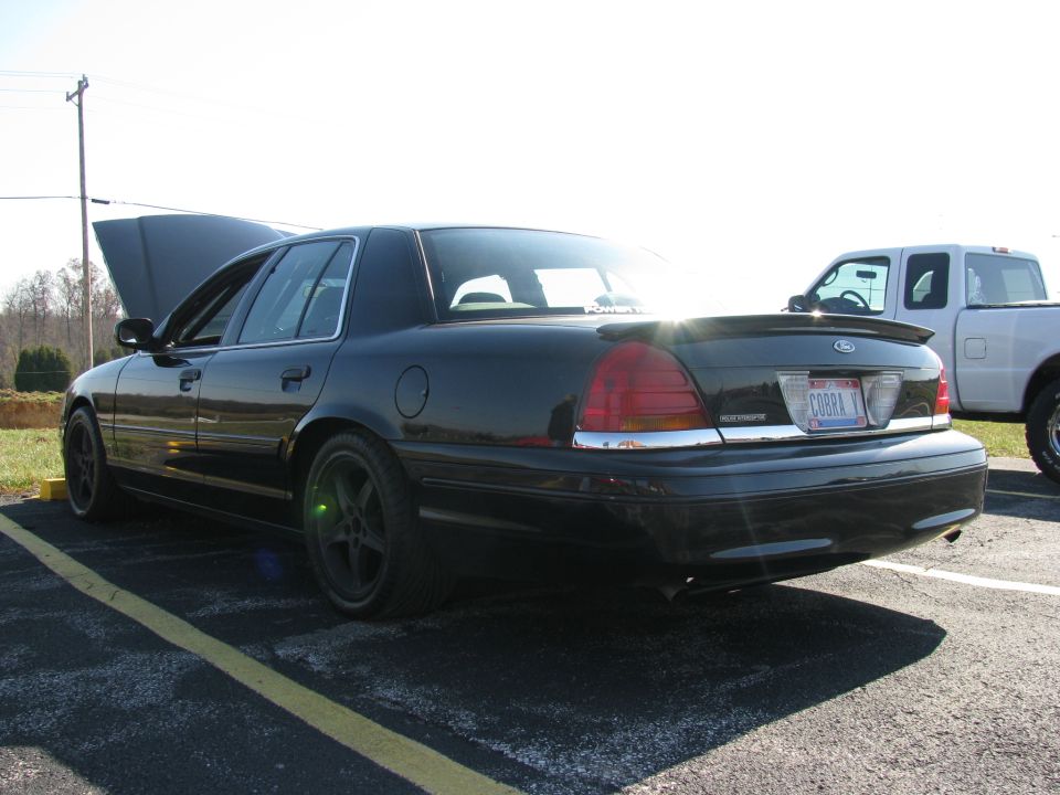 Black Ford Crown Victoria Police Interceptor sedan, hood open, COBRA V plate, dark five-spoke wheels