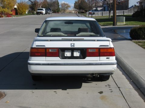 1989 Honda Accord - The rear of a white Honda Accord sedan is shown, with a spoiler and taillights visible.