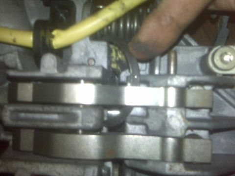 1995 Ford Bronco - A close-up view of an engine part, possibly a carburetor, with a yellow hose and a finger interacting with it.