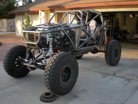 2009 Suzuki Samurai - A custom-built buggy with a prominent roll cage and oversized tires sits in a residential driveway.