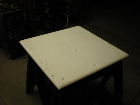 Suzuki Samurai - A white panel, possibly a car part, rests on sawhorses in a workshop.