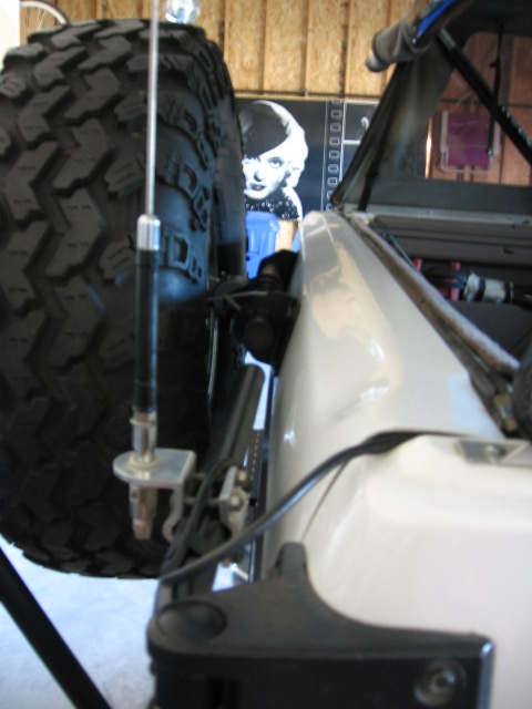 1995 Ford Bronco - Close-up of a spare tire carrier mount on a white vehicle, showing the tire and antenna.