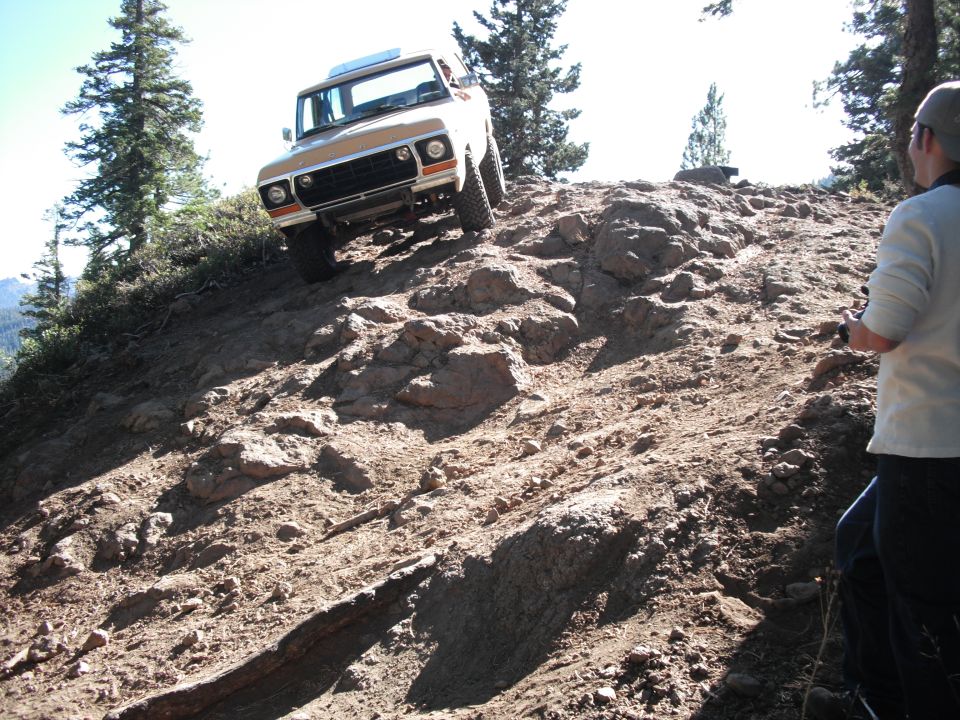 Tan and white Ford Bronco climbing a rocky hill