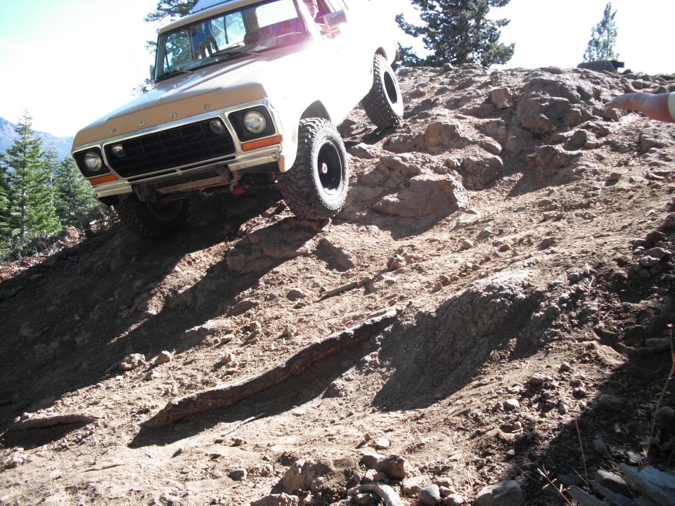 1978 Ford Bronco climbing a steep, rocky hill. Front grille and headlights visible