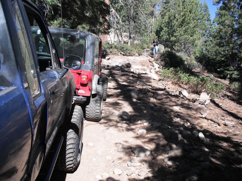 Blue pickup truck and red Jeep on a rocky mountain trail