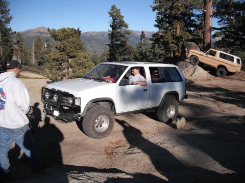 1991 Ford Bronco - White Nissan Pathfinder navigating rocks on a trail, with a tan Ford Bronco parked on a boulder.