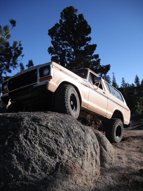 1991 Ford Bronco - A tan Ford Bronco is positioned on a large rock with a clear blue sky overhead.