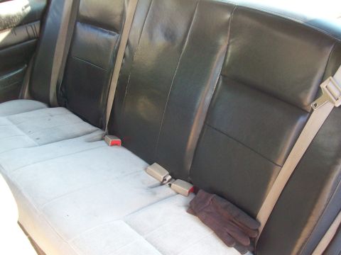 2004 Ford Crown Victoria - The interior of a car shows the rear bench seat and seatbelts.