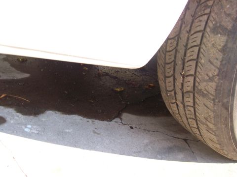 2004 Ford Crown Victoria - Tire and puddle visible next to the lower body panel of a white vehicle.