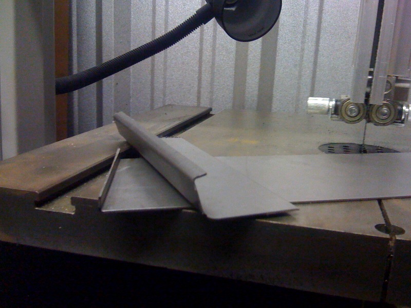metal pieces on a band saw table, ready for cutting