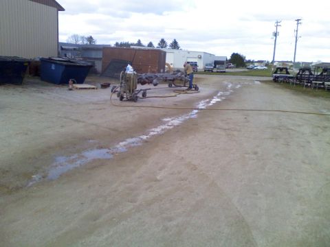1979 Ford F-250 - A vehicle frame is being sandblasted outdoors next to a building.