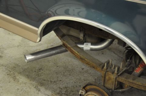 1996 Ford Bronco - The underside of a vehicle shows its rear suspension and exhaust system, with a label on the new exhaust pipe.