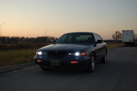 1985 Mercury Grand Marquis - This dark blue sedan features an aftermarket grille and headlights, with a license plate that reads B1DMSLOW.