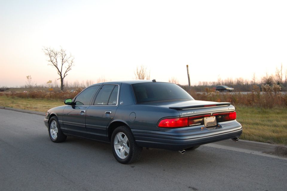 Blue sedan with a spoiler parked on the side of a road