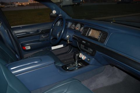 1985 Mercury Grand Marquis - The interior of the vehicle features blue upholstery and a dashboard with a navigation screen and gauges.