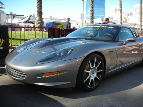 1998 Ford Crown Victoria - This Corvette C6 is on display at an outdoor event with palm trees and buildings in the background.