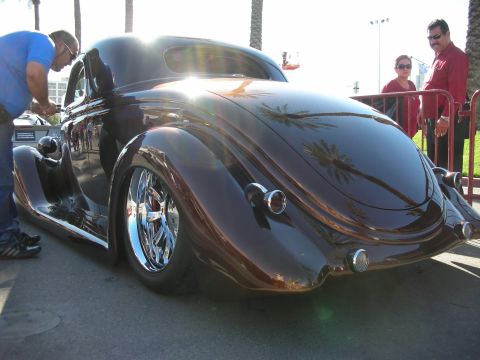 1998 Ford Crown Victoria - A custom hot rod coupe with a dark brown finish and chrome wheels is viewed from the rear.