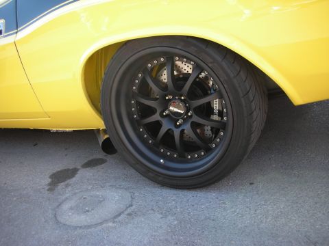 1998 Ford Crown Victoria - Close-up of a yellow car's wheel and fender, showing custom modifications.