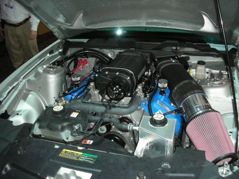 1998 Ford Crown Victoria - Customized engine bay a prominent supercharger and aftermarket air intake system on a silver vehicle.