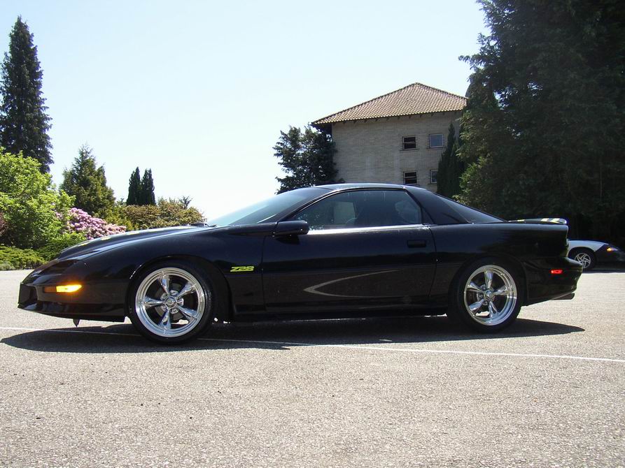 Black Chevrolet Camaro Z28 coupe side profile with chrome wheels on pavement