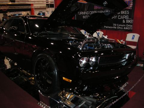 1998 Ford Crown Victoria - A black Dodge Challenger is displayed with its hood open, revealing a custom engine and lowered suspension.