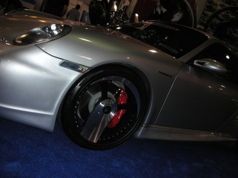 1998 Ford Crown Victoria - A silver sports car with custom wheels and red brake calipers is displayed on a blue carpeted surface.