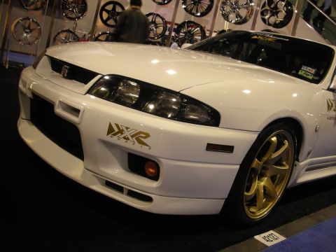 1998 Ford Crown Victoria - A white sports car with distinctive gold wheels and aftermarket decals is displayed indoors.