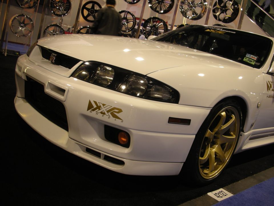 White sports car with gold wheels and 'XKR Wheels' decal