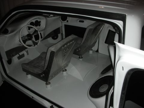 1998 Ford Crown Victoria - The interior of a custom car features white upholstery, a unique steering wheel, and exposed speakers.